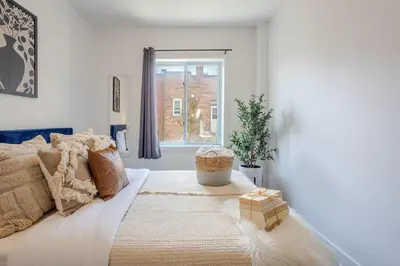 a white bedroom with a bed with a window at Wonderful 4 BR Home in the heart of Downtown in Montréal