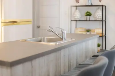 a kitchen counter with a sink and some chairs at Luxurious 4 BR Suite in Griffintown in Montréal