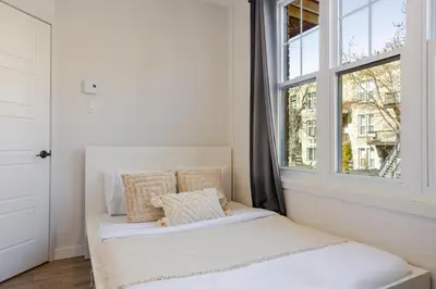 a white bed in a room with a window at Warm 2BR in the Heart of Plateau MTL in Montréal