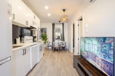 a kitchen with white cabinets and a flat screen tv at The Perfect Downtown Hideaway in Montréal