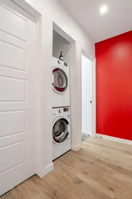 a laundry room with two washing machines and a red wall at Spacious 4BR 2BA in the Plateau Montreal in Montréal