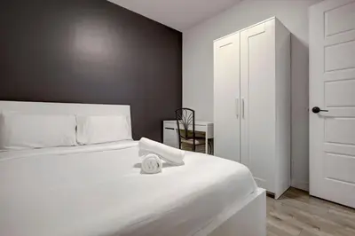a white bedroom with a white bed and a table at Vibrant 4BR 2BA Retreat in the Plateau in Montréal