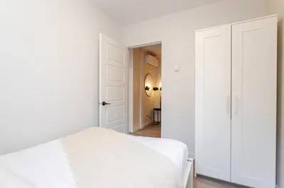 a white bedroom with a bed and an open door at Stunning 3BR on in Plateau Mont-Royal in Montréal