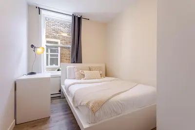 a white bedroom with a bed and a window at Stunning 3BR on in Plateau Mont-Royal in Montréal