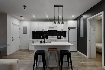 a kitchen with white cabinets and a counter and stools at Elegant 4BR on in the Plateau MTL in Montréal