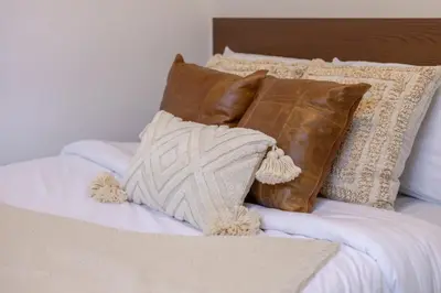 a bed with brown and white pillows on it at Amazing 3-Bedroom on Saint-Urbain in Montréal