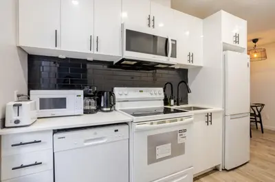 a kitchen with white cabinets and white appliances at Beautiful 3BR in MTL Mont-Royal in Montréal