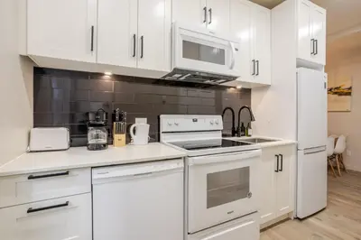 a kitchen with white cabinets and a stove top oven at Bright 3BR 2BA in the Plateau in Montréal