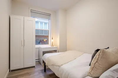 a white bedroom with a bed and a window at Bright 3BR 2BA in the Plateau in Montréal