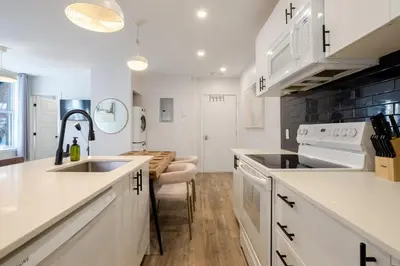 a kitchen with white cabinets and a sink and a table at Charming 3BR in the Plateau MTL in Montréal