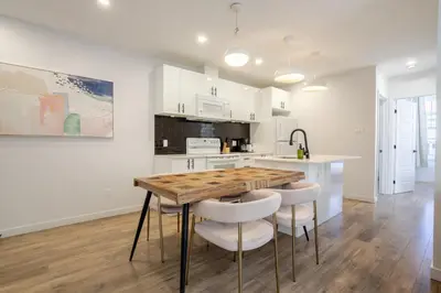 a kitchen with white cabinets and a wooden table and stools at Charming 3BR in the Plateau MTL in Montréal
