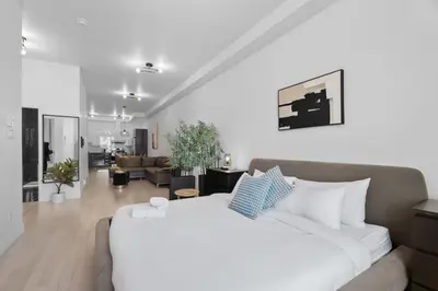 a bedroom with a large white bed and a living room at New Modern 2bdr Apartment in Little Italy Unit 202 in Montréal