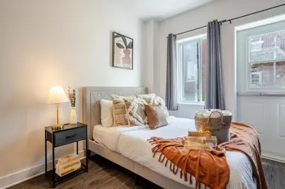 a bedroom with a bed with a nightstand and a window at Large Suite in Downtown Montreal in Montréal