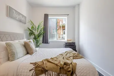 a white bedroom with a bed and a window at Large Suite in Downtown Montreal in Montréal