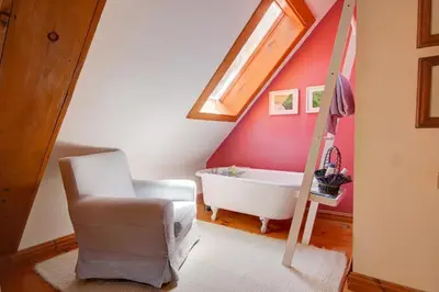 a bathroom with a bath tub and a chair at Détente au coeur de la forêt in Mansonville