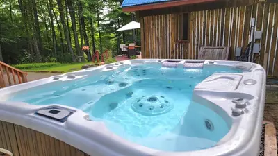 a hot tub in front of a house at Détente au coeur de la forêt in Mansonville