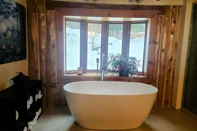 a bath tub in a room with a window at Détente au coeur de la forêt in Mansonville