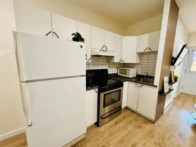 a kitchen with a white refrigerator and white cabinets at Luxe Living Stay in Montréal