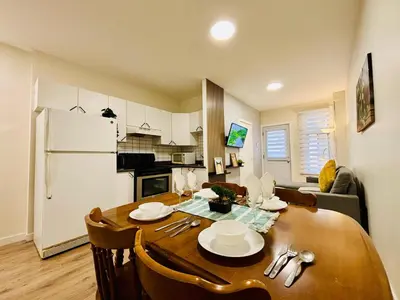 a kitchen and living room with a wooden table and a dining room at Luxe Living Stay in Montréal