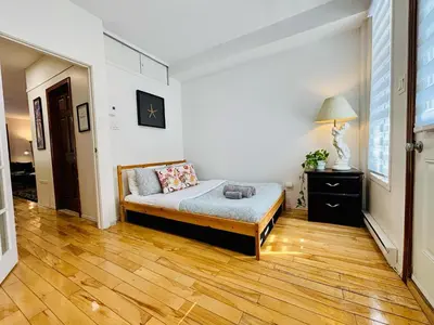 a bedroom with a bed and a wooden floor at Freshly Renovated Stay in Montréal