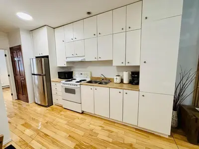 a kitchen with white cabinets and a refrigerator at Freshly Renovated Stay in Montréal