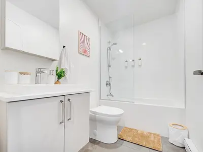 a white bathroom with a toilet and a shower at Terracotta 1-BD in Downtown MTL in Montréal