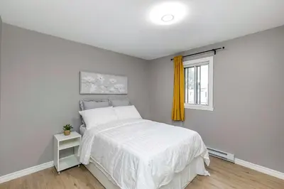 a bedroom with a white bed and a window at Three bedroom apartment Free parking EV charger in Longueuil