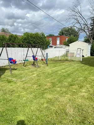 a yard with a swing set in the grass at Three bedroom apartment Free parking EV charger in Longueuil