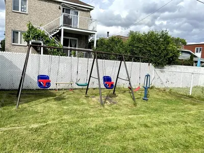 an empty swing set in a yard next to a fence at Three bedroom apartment Free parking EV charger in Longueuil