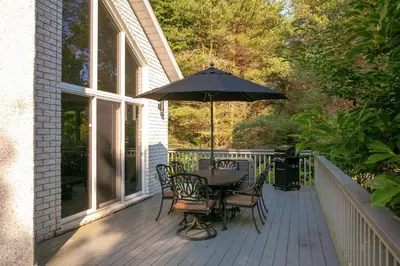a table and chairs with an umbrella on a porch at CHALET Le HAVRE NATURE SPA in Mansonville