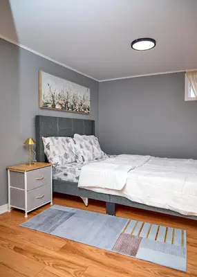 a bedroom with a bed and a dresser in it at Grande maison moderne 4 chambres - Spa Jaccuzi, Jardin & Parking gratuit - Idéale Familles et groupes in Saint-Jean-sur-Richelieu