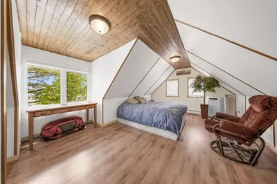 a attic bedroom with a bed and a chair at Havre du Huit in Adstock