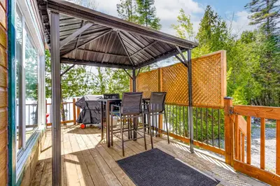 a screened in deck with a table and chairs at Havre du Huit in Adstock