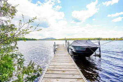 a boat tied up to a dock on a lake at Havre du Huit in Adstock