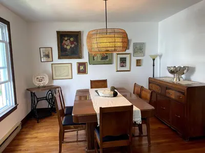 a dining room with a table and chairs and a chandelier at Grande Maison Vintage à Ange Gardien Sortie 55 Autoroute 10 in Ange-Gardien