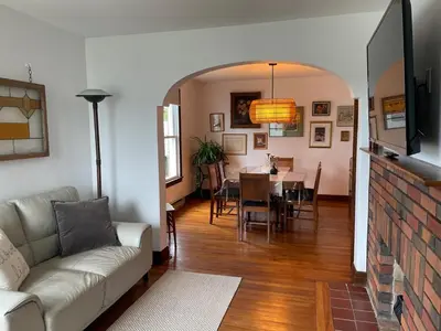 a living room with a couch and a dining room at Grande Maison Vintage à Ange Gardien Sortie 55 Autoroute 10 in Ange-Gardien
