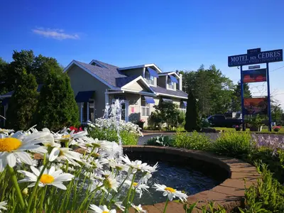a house with a pond in a garden with flowers at Motel des Cèdres in Sherbrooke