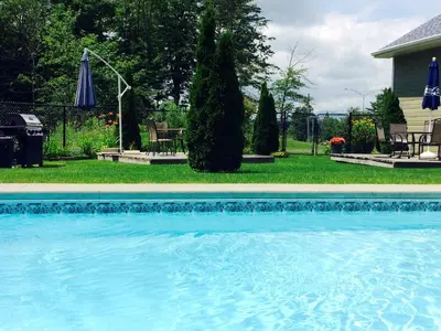 a swimming pool with blue water in a yard at Motel des Cèdres in Sherbrooke