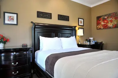 a bedroom with a large bed and a dresser with a bed sidx sidx sidx at Motel des Cèdres in Sherbrooke