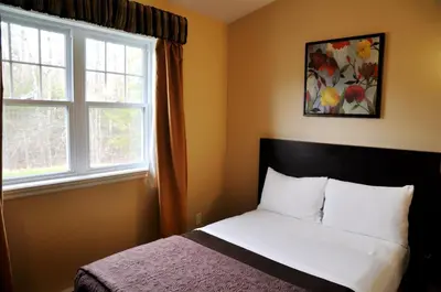 a bedroom with a bed and two windows at Motel des Cèdres in Sherbrooke
