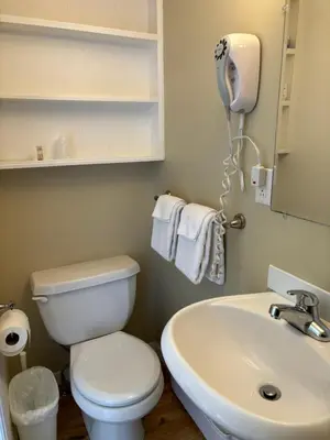 a bathroom with a white toilet and a sink at Motel des Cèdres in Sherbrooke