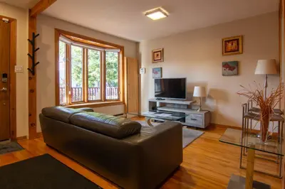 a living room with a leather couch and a television at Cozy Bungalow Longueuil - 3 BR - 6 pers in Longueuil