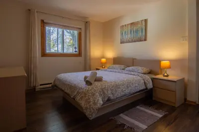 a bedroom with a bed with two lamps and a window at Cozy Bungalow Longueuil - 3 BR - 6 pers in Longueuil