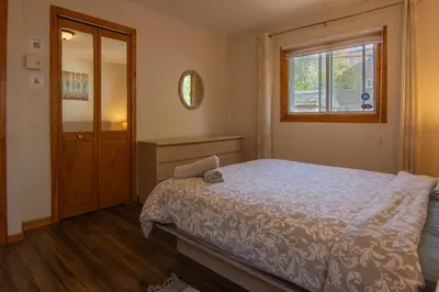 a bedroom with a bed and a window and a mirror at Cozy Bungalow Longueuil - 3 BR - 6 pers in Longueuil