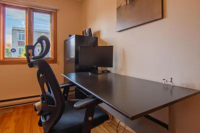 a black desk with a computer monitor and a chair at Cozy Bungalow Longueuil - 3 BR - 6 pers in Longueuil