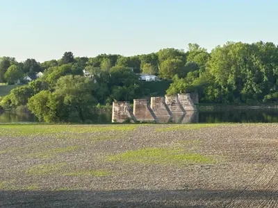an old dam on a river with trees in the background at Motel Le Villageois Du Lac in Saint-Francois-du-Lac
