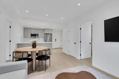 a living room with a table and a kitchen at Le Victoria Midtown Mtl in Montréal