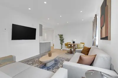 a white living room with a couch and a table at Le Victoria Midtown Mtl in Montréal