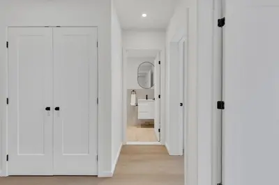 a hallway with white walls and a white bathroom at Le Victoria Midtown Mtl in Montréal