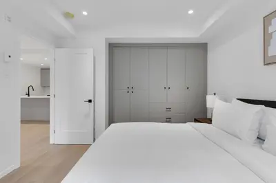 a white bedroom with a large bed and white cabinets at Le Victoria Midtown Mtl in Montréal